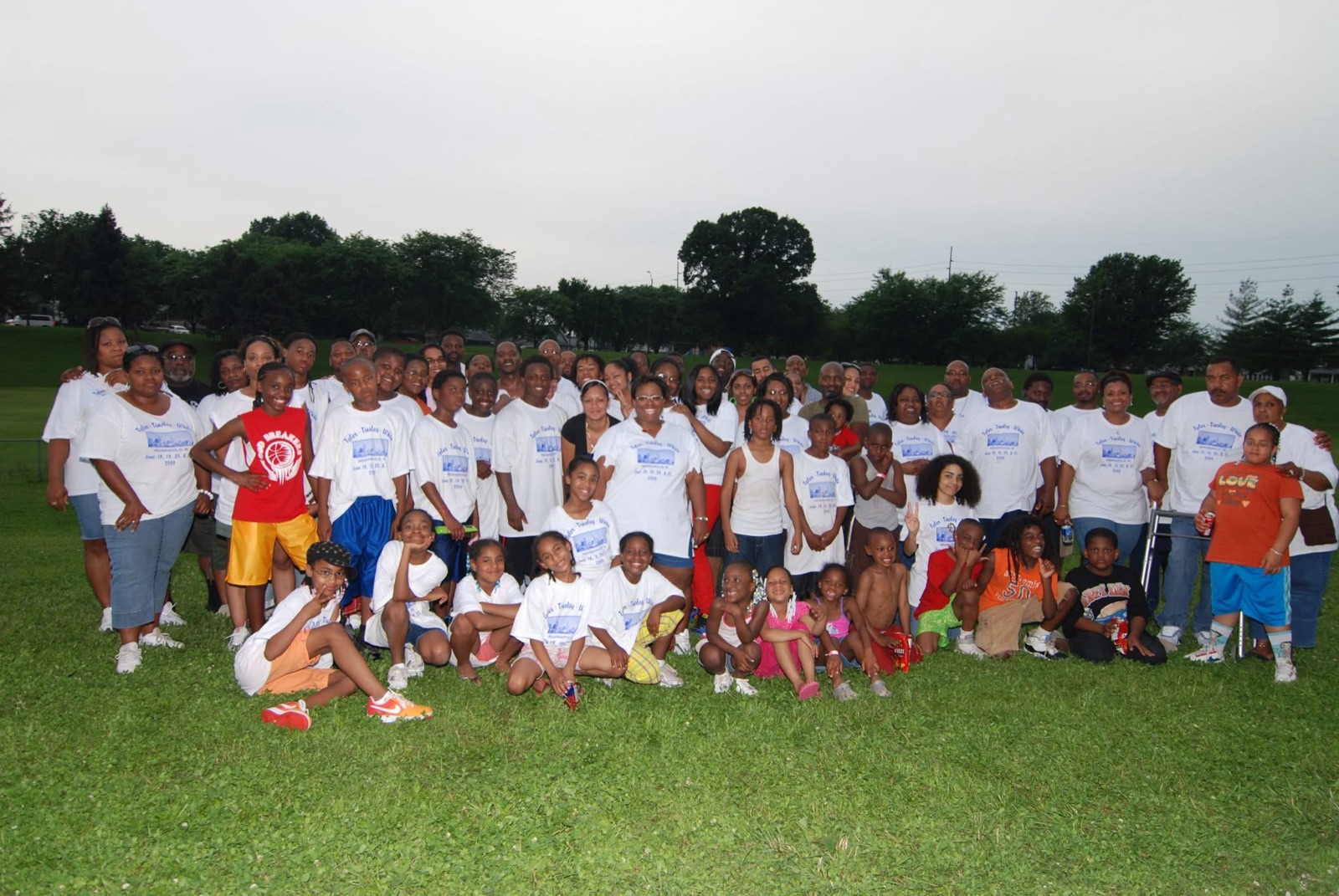 Family group photo on a grassy field in matching reunion shirts